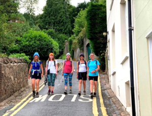 A group of walkers stride down a hilly road at the end of the Worcestershire Way Walk.
