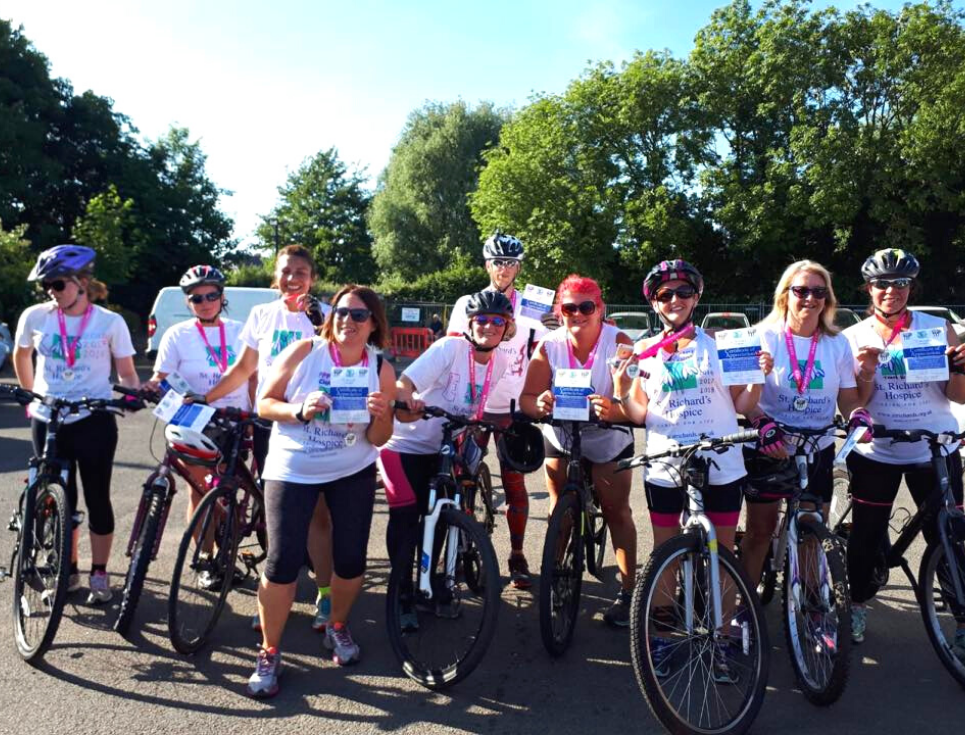 A group of people stand together with their bicycles. They have taken part in the hospice's Paddle, Plod and Pedal challenge.