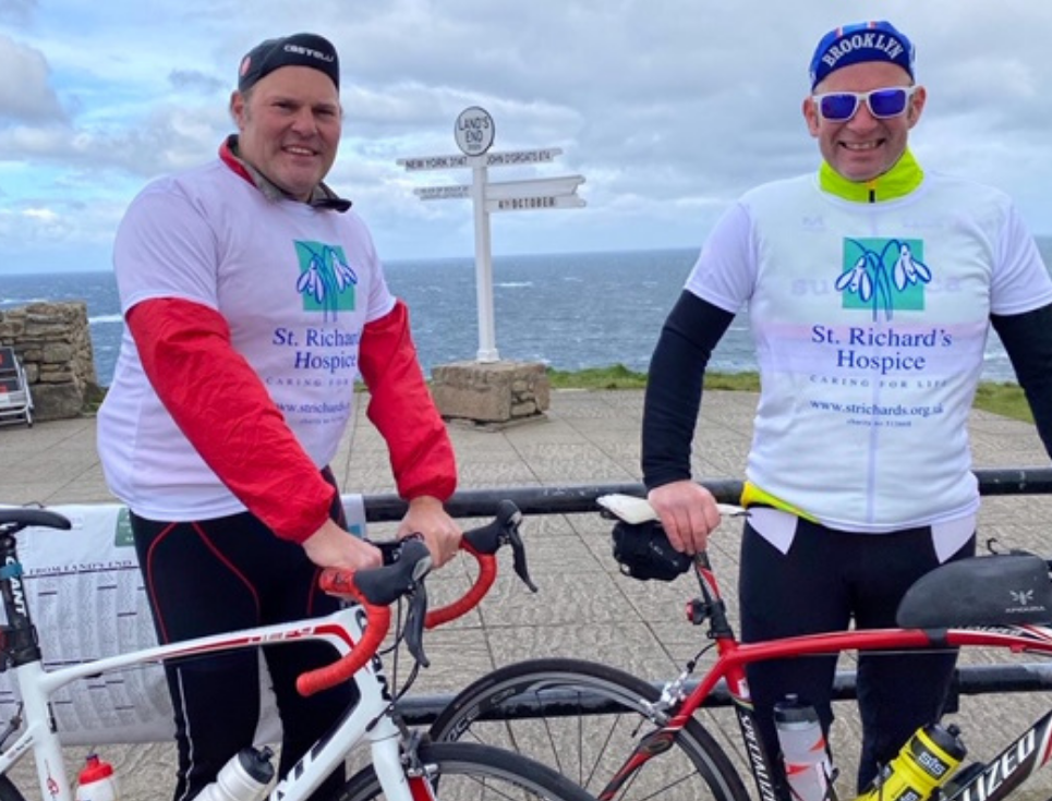 Two people wearing St Richard's Hospice logo t-shirts standing next to their bicycles