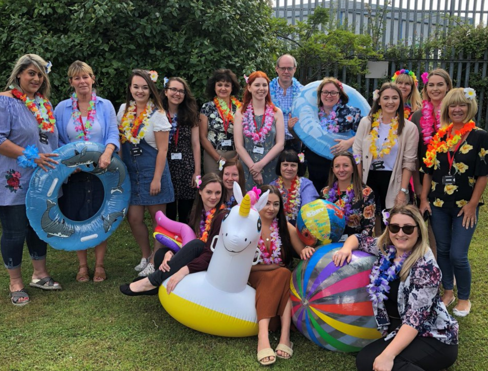 This button takes you through to a page with information about fundraising at work. The picture shows a group of people wearing holiday clothes, stood together in a garden.