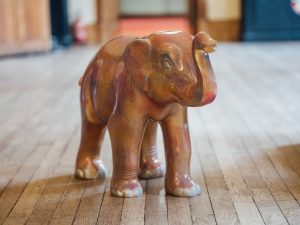 A small, pink elephant sculpture stands on wooden floor boards in the grand surroundings of Worcester's Guildhall.