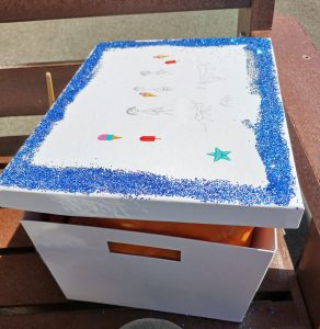 A white box, outlined in bright blue glitter. This is a memory box used to help people cope with their bereavement.