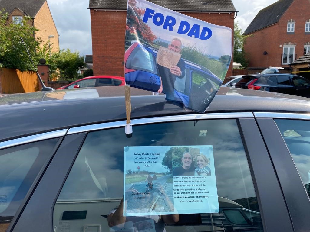 A black car with a flag showing a picture of Pete Breakwell and the words 'For Dad' in blue lettering.