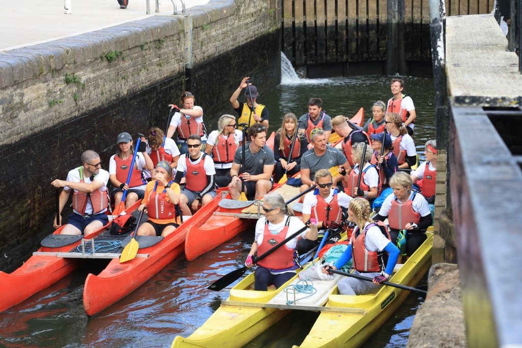 groups of people sitting in orange and yellow bell boats on the river