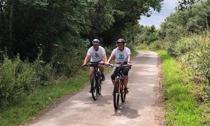 two people riding bicycles along a country lane