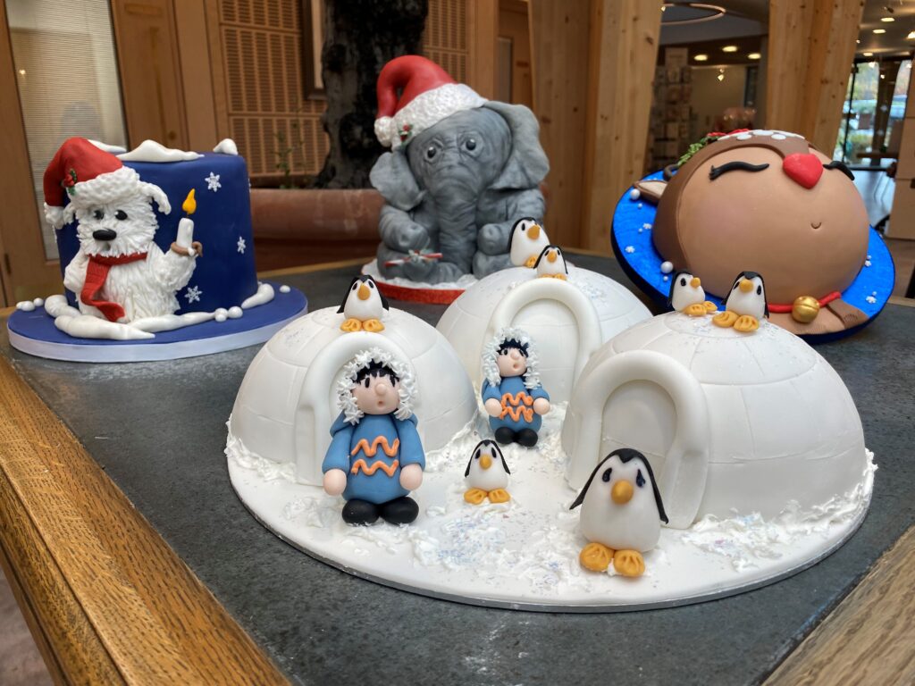 A selection of elaborately iced Christmas cakes sit on a table.