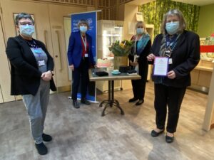 Four people stand together wearing blue face masks.