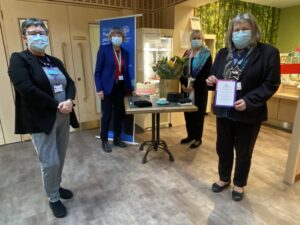 Four people stand together wearing blue face masks. 