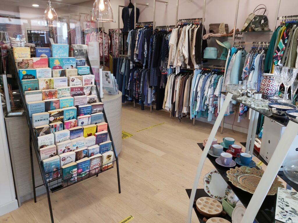 The inside of the St Richard's Hospice shop in Bromsgrove. There is a large rack of books on display, alongside rails of clothing and shelves of bric-a-brac.