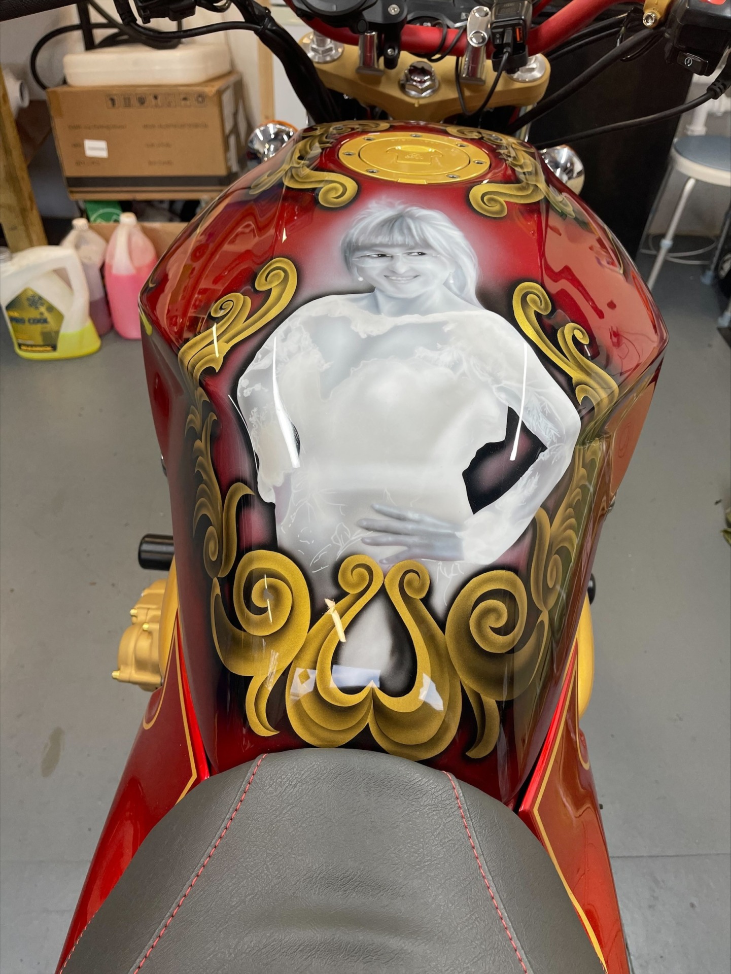 A black and white painting of Janet Kirk, featured on a red and gold motorbike.