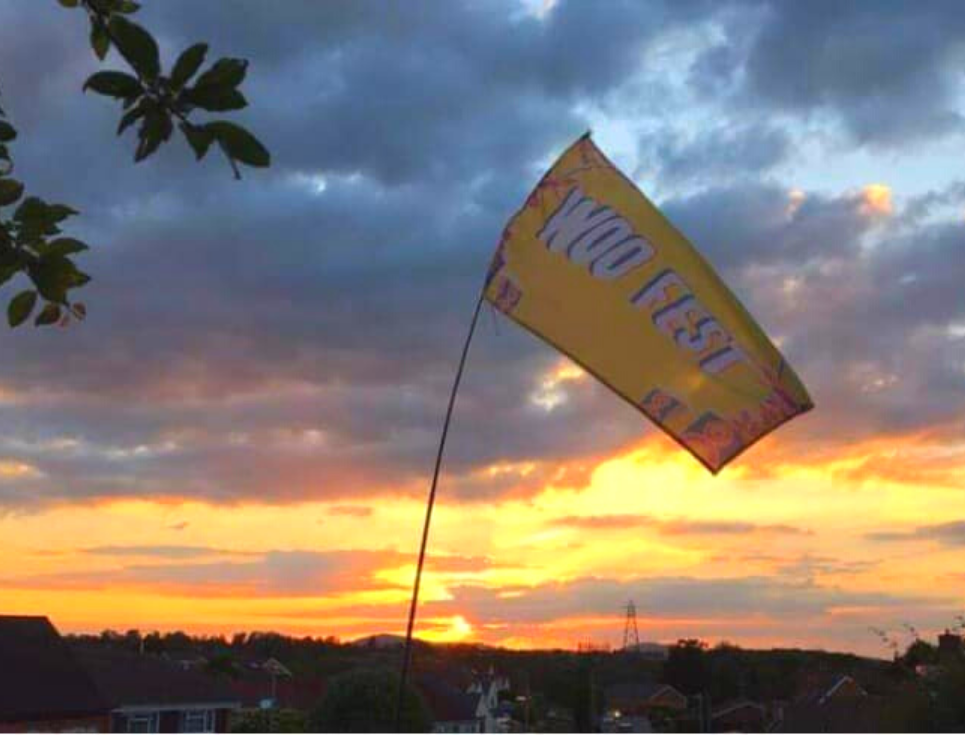 The yellow Woo Fest flag flies against a blue and gold evening sky.