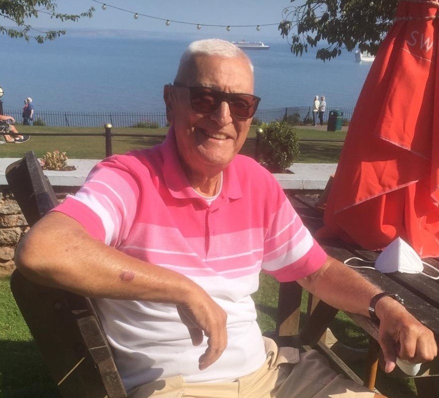 John E Parkinson pictured on a sunny day. He wears a red and white t-shirt, and sunglasses.