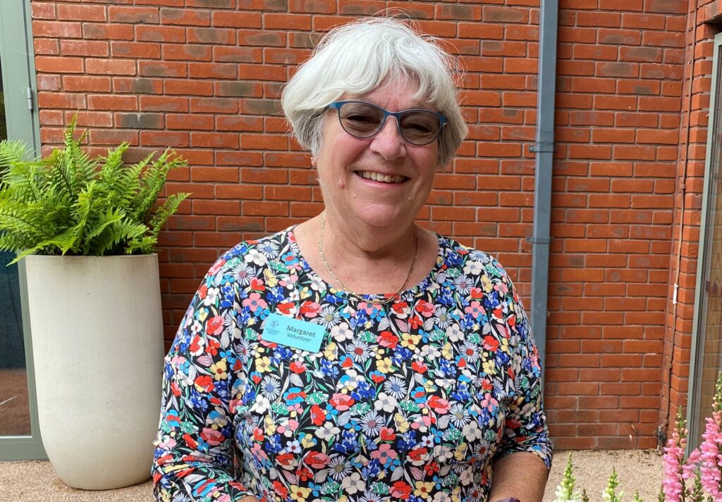 Margaret, a Living Well volunteer, stands in the hospice's courtyard garden.