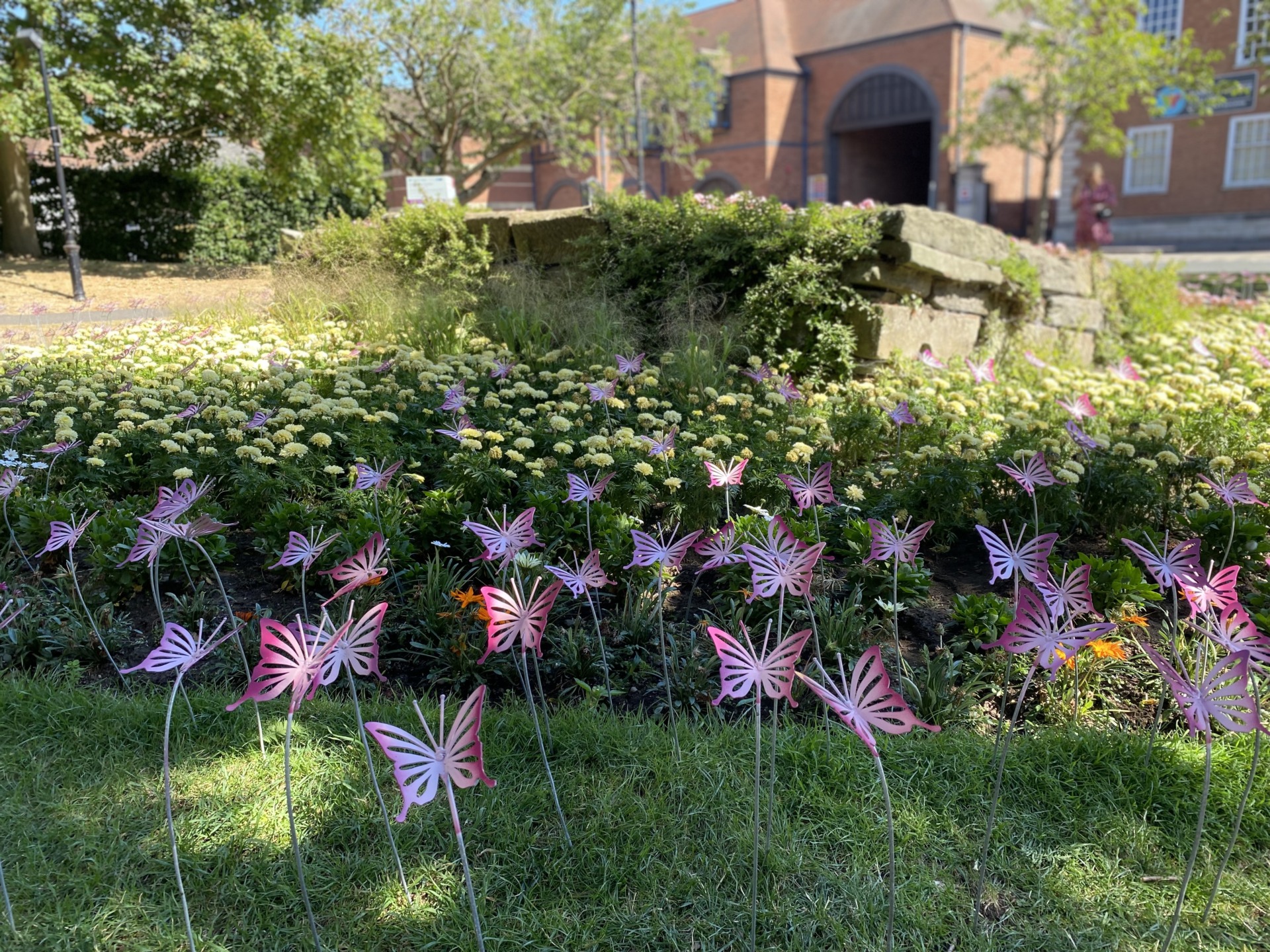 Pink butterfly sculptures on display in the flower beds in front of St Andrew's Spire, Worcester