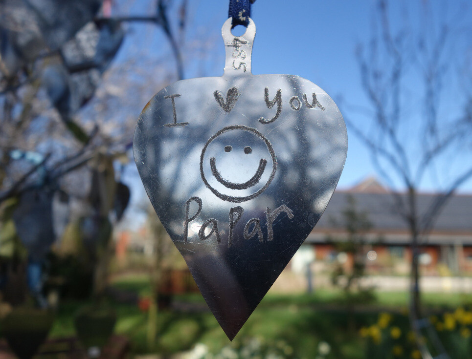 silver heart shape hanging from tree with I love you papar wording engraved on it
