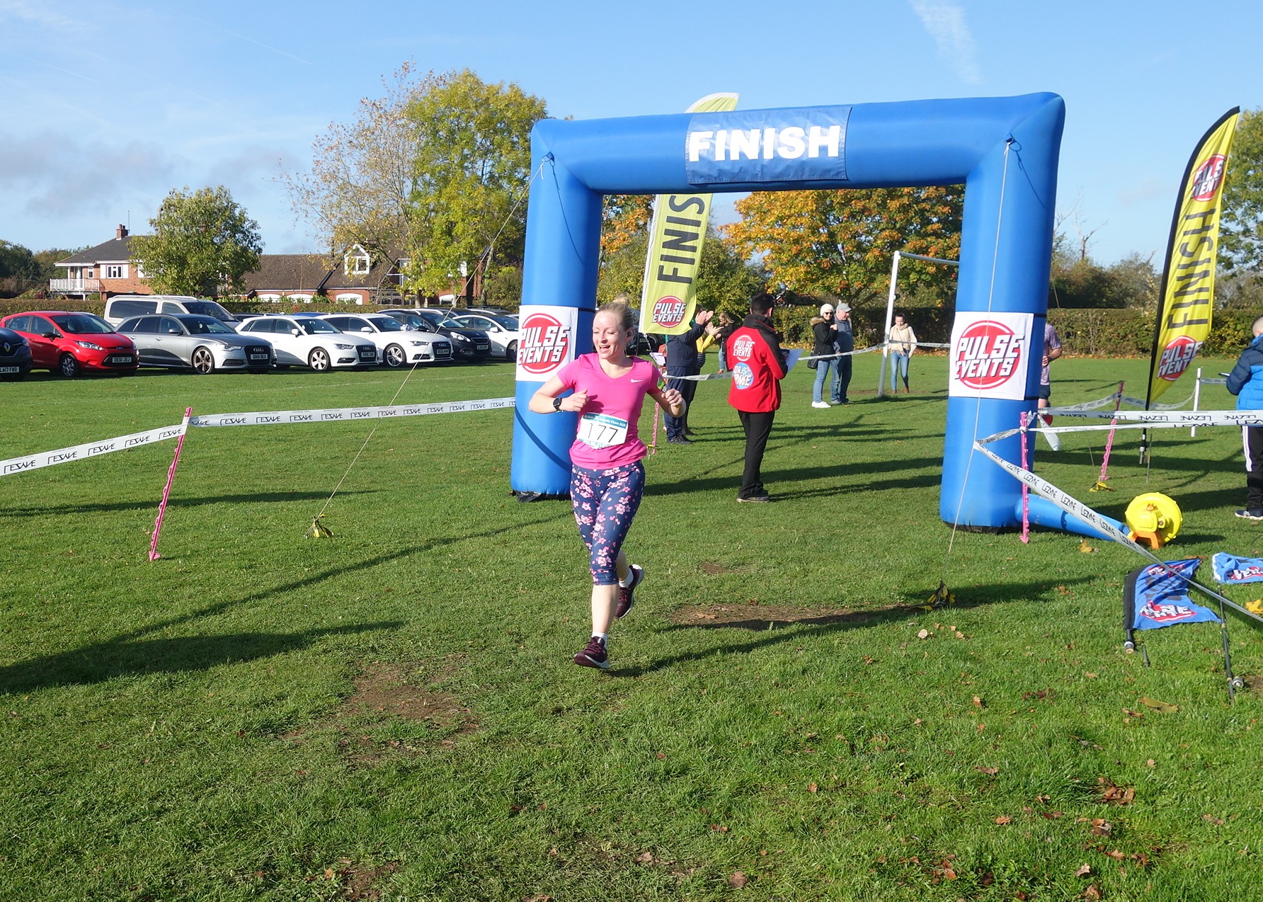 A runner crosses the finish line of the Cupcake Chase. Behind her is a large, inflatable blue arch with the word 'finish' emblazoned on it.