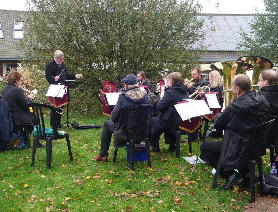 Worcester Concert Brass perform in the gardens of St Richard's Hospice on a grey-skied day.