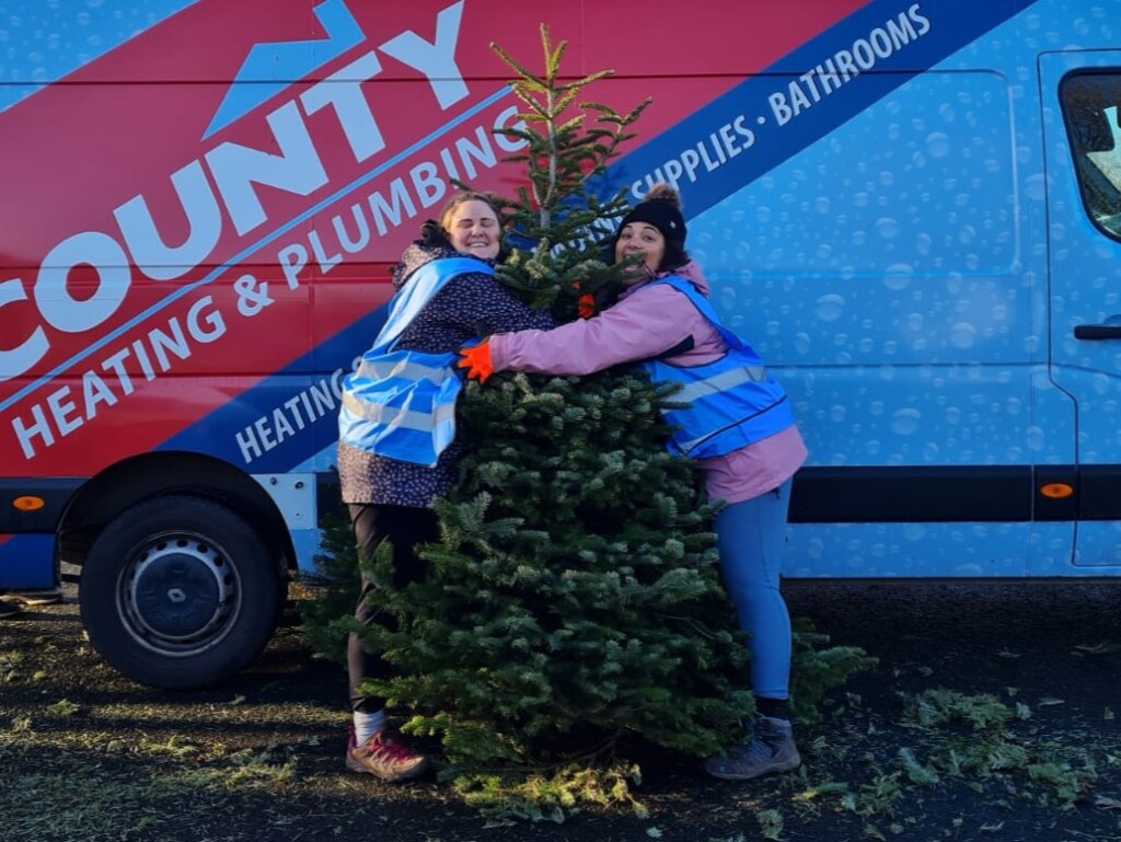 Two people hug a Christmas tree