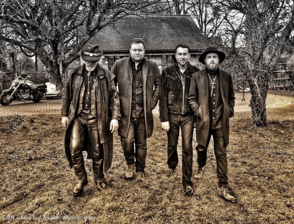 Four band members of Vincent Flatts standing in a row in a dark atmospheric photo.