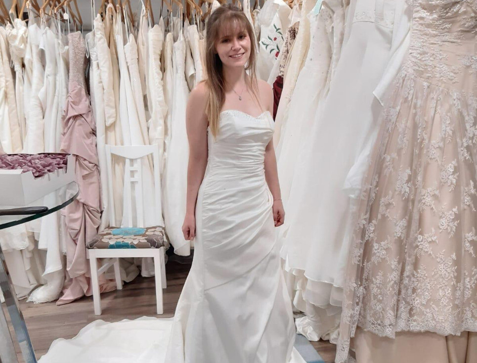 Woman modelling a wedding gown surrounded by wedding dresses