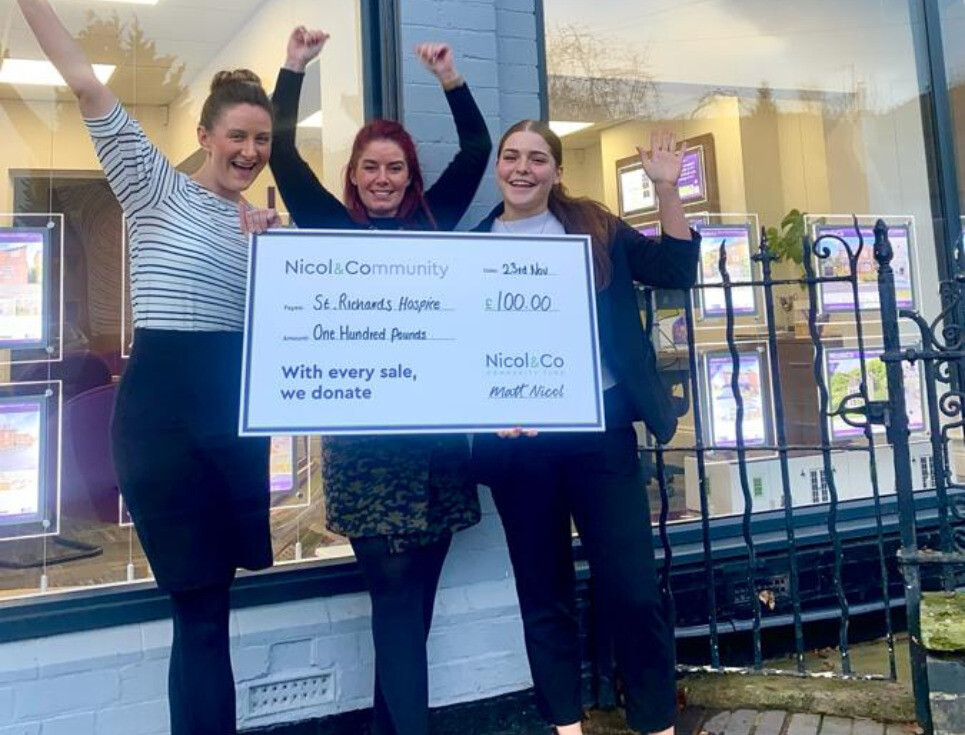 Three people stand together outside Nicol and Co Estate Agents holding a giant cheque for one hundred pounds to St Richard's.