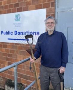 Man holding a gardening tool in front of sign reading public donatons