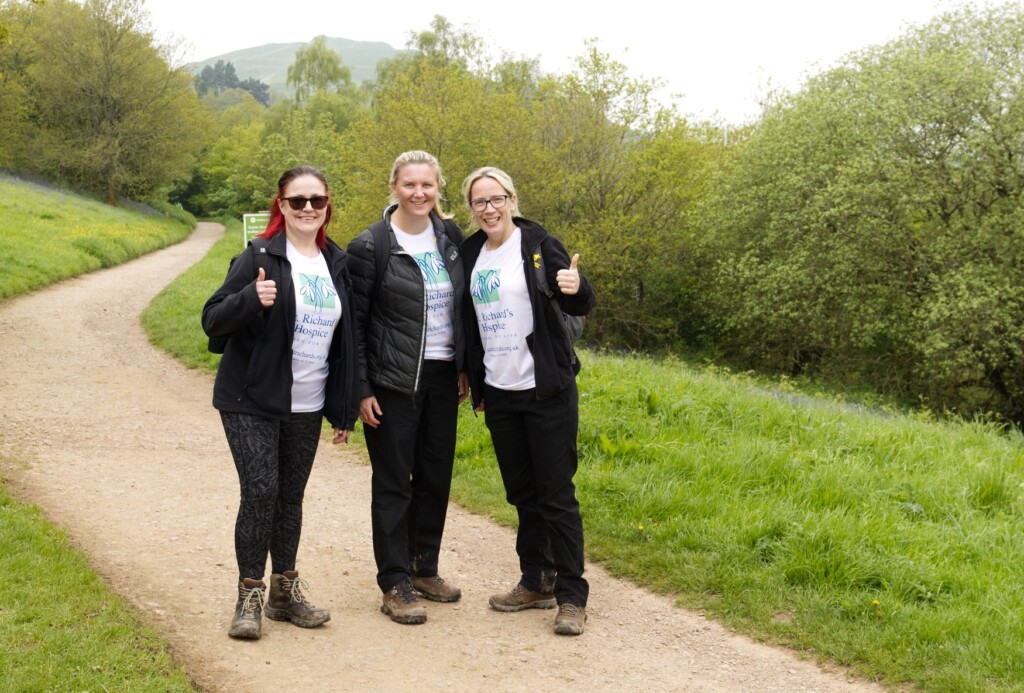 Three people taking part in the Malvern Hills Walk. They wear St Richard's Hospice branded t-shirts.