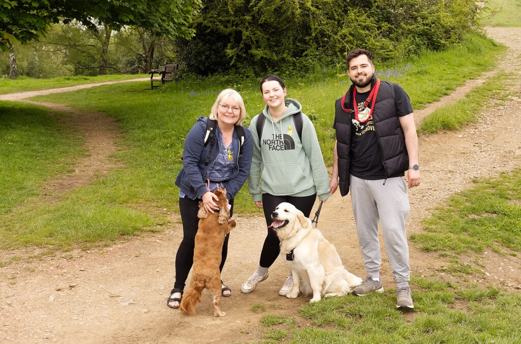 Three people taking part in the Malvern Hills Walk with two dogs.