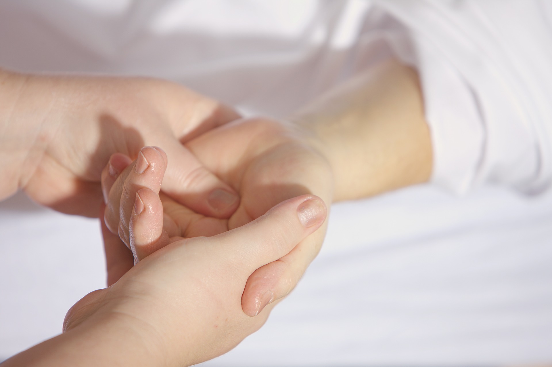 Two hands hold another person's hand, demonstrating the M Technique.