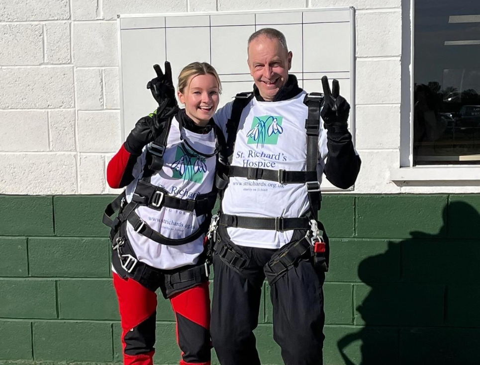 Two sky divers male and female, in St Richard's Hospice T shirts, in their harnesses ready to jump.