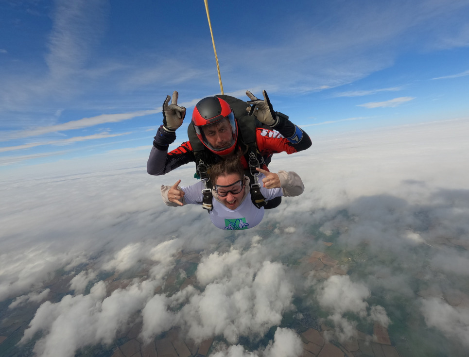 A female skydiver free falling through the air with an instructor.