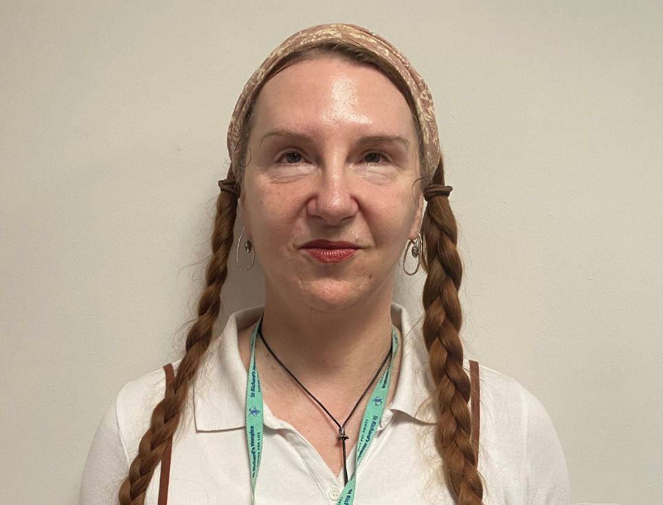 Ingrid pictured against a plain white wall. She has her hair in two long plaits and is wearing a white shirt.