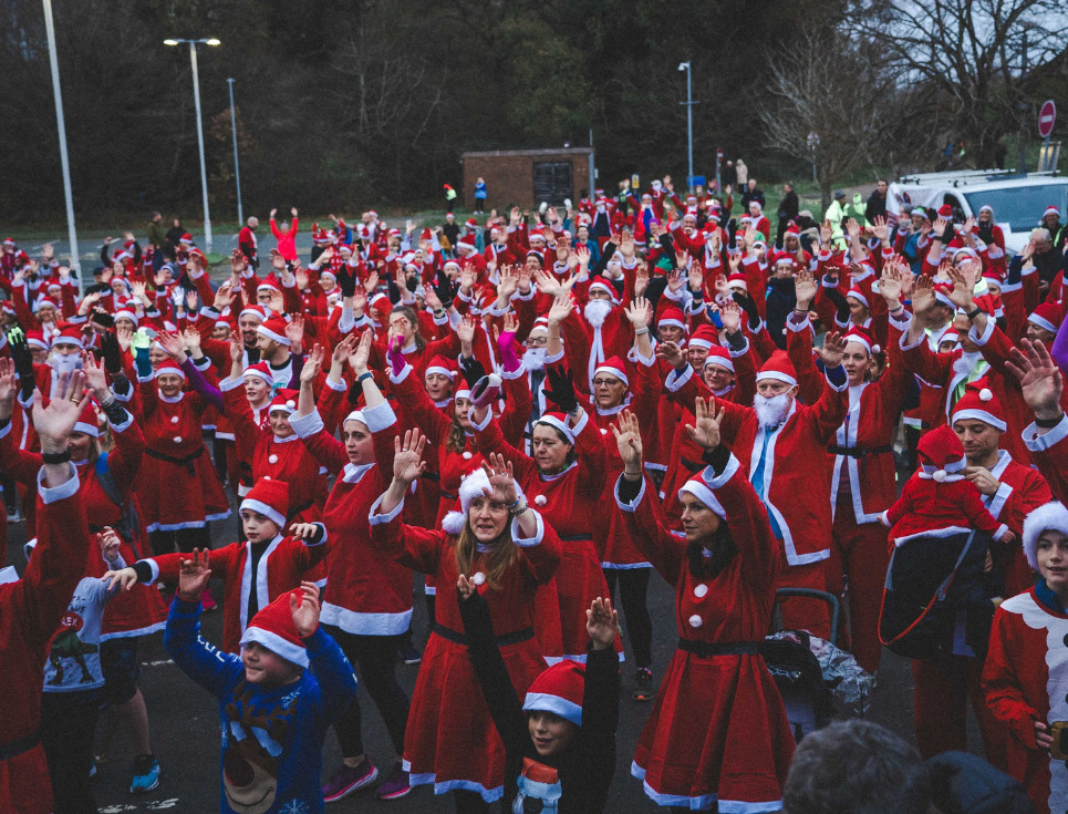 A large group of people dressed as Santa taking part in a group warm up
