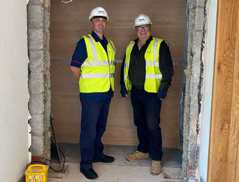 Jamie Yeomans, IPU Manager, and Paul Morris, Speller Metcalfe Site Manager stand together in a doorway which has been widened and is in the process of being constructed. They are both wearing high-vis jackets and hard hats.