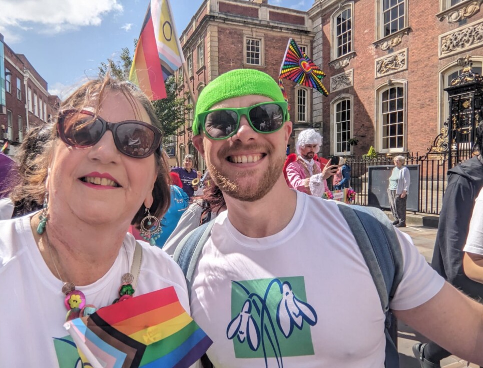 Two people wearing St Richard's Hospice branded t-shirts take part in the Worcestershire Pride parade through Worcester's High Street.