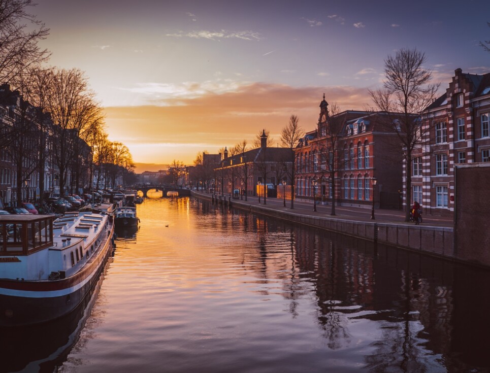 Large Canal in Amsterdam at sunset, with the sunset reflecting onto the water.