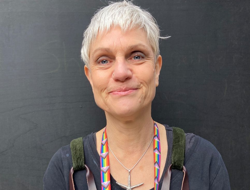 Sally pictured against a black background. She has short, white hair. She is smiling.