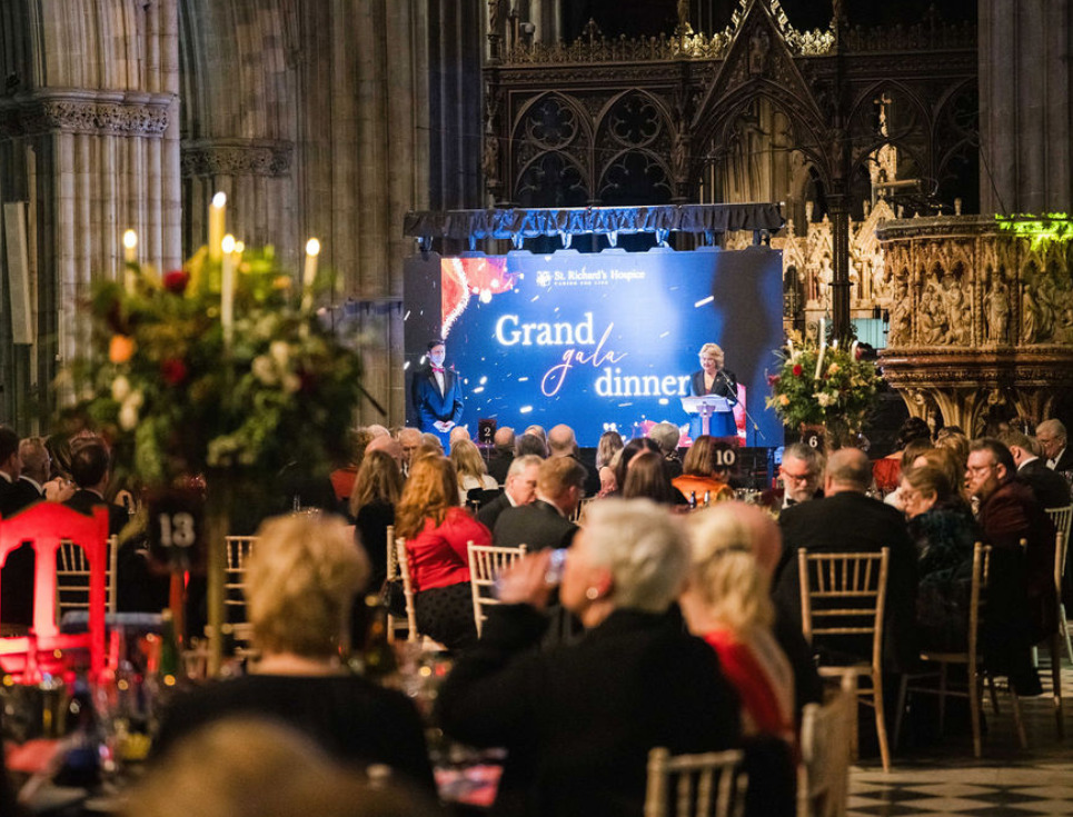 Guests seated around tables in the Nave of Worcester Cathedral at the hospice's Grand Gala Dinner.
