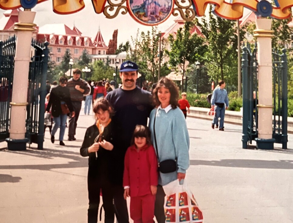Two children with parents standing in front of an arch with the sign Euro Disneyland in 1994