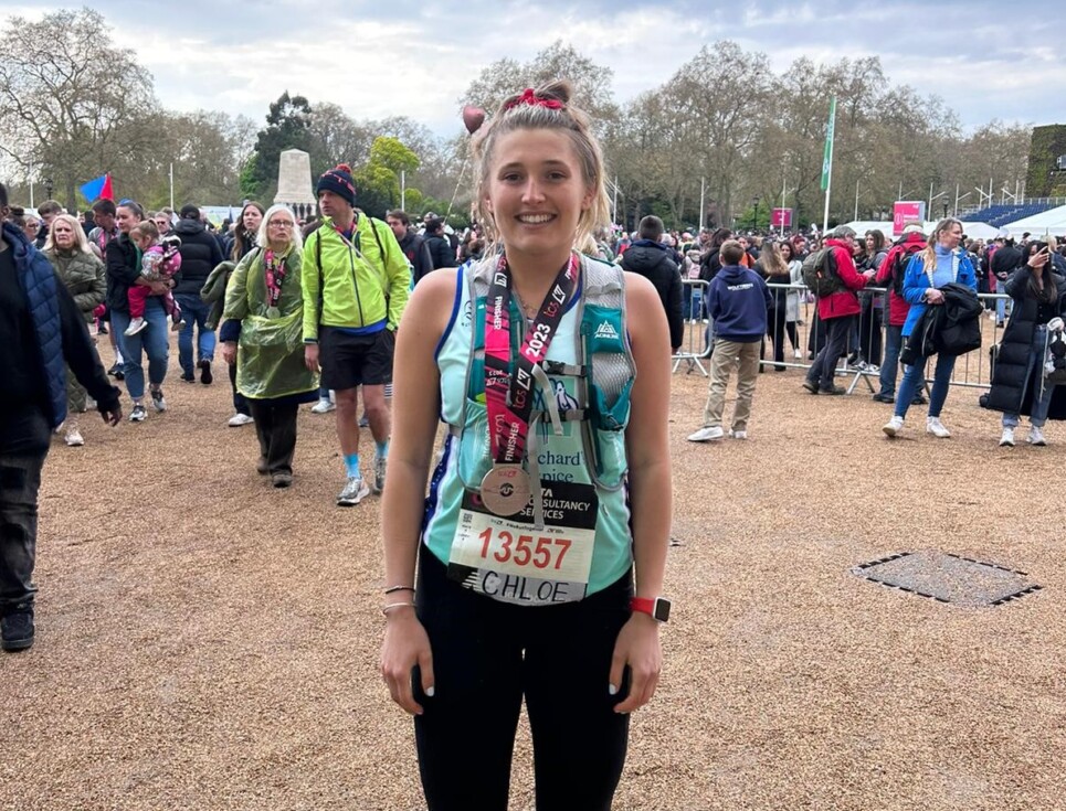 Chloe pictured in her running gear and with her London Marathon medal around her neck. She is smiling.