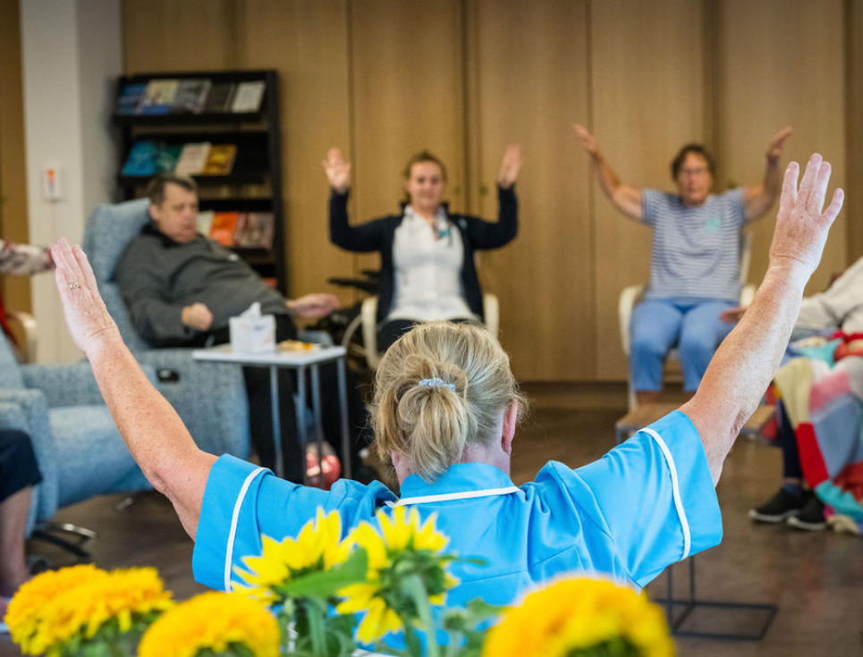 A group of people take part in a seated Tai Chi session in the hospice's Living Well Centre.