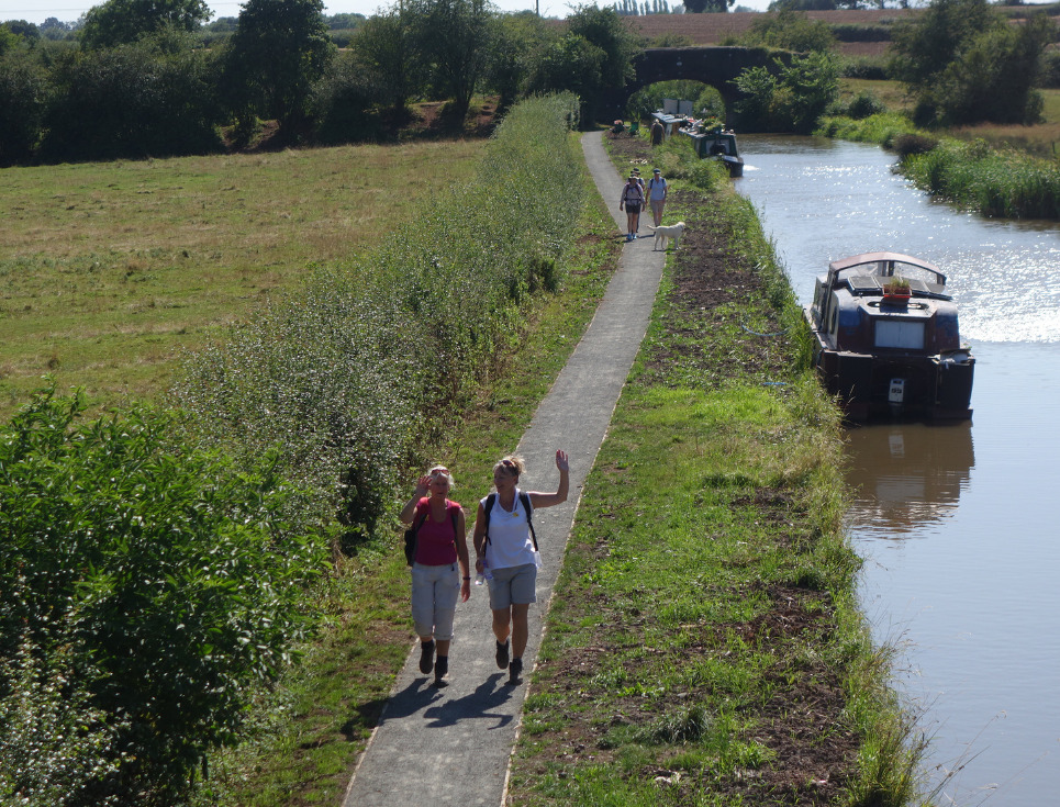 Two people walking alongside a river with their hands in the air joyfully.