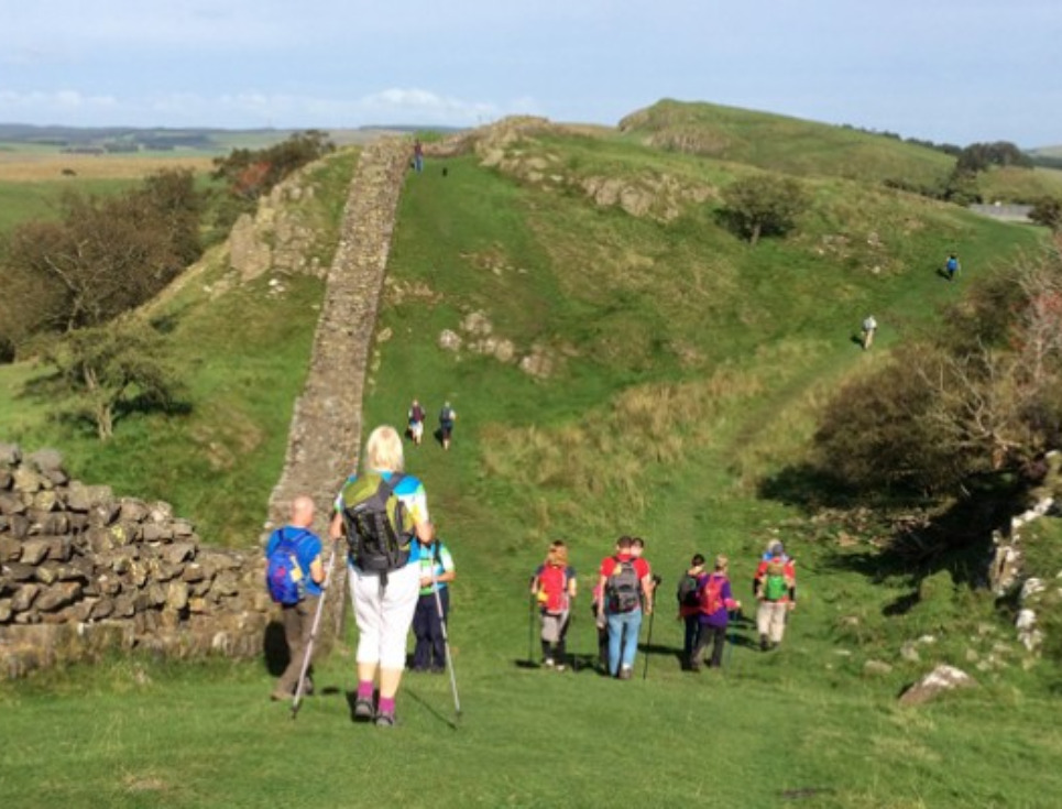 A large group of walkers trekking along Hadrian's Wall