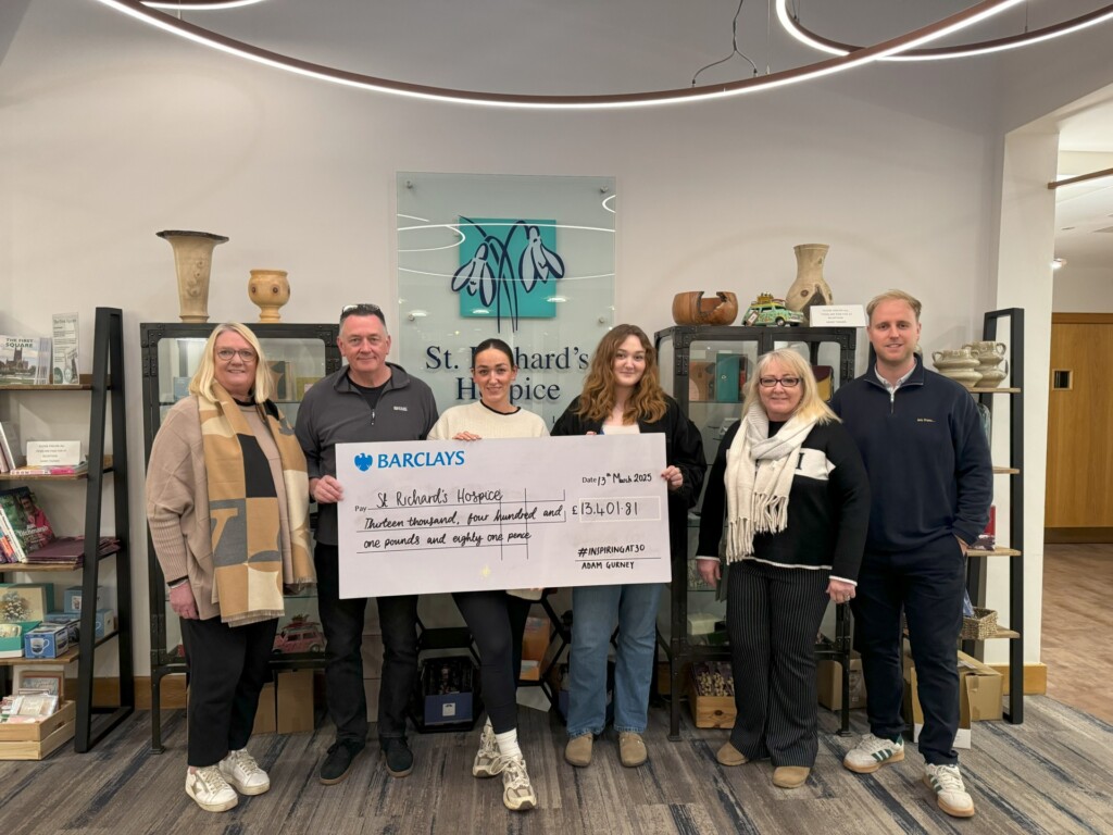 A group of people with a large cheque stand in Reception at St Richard's Hospice.