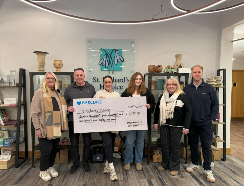 A group of people with a large cheque stand in Reception at St Richard's Hospice.