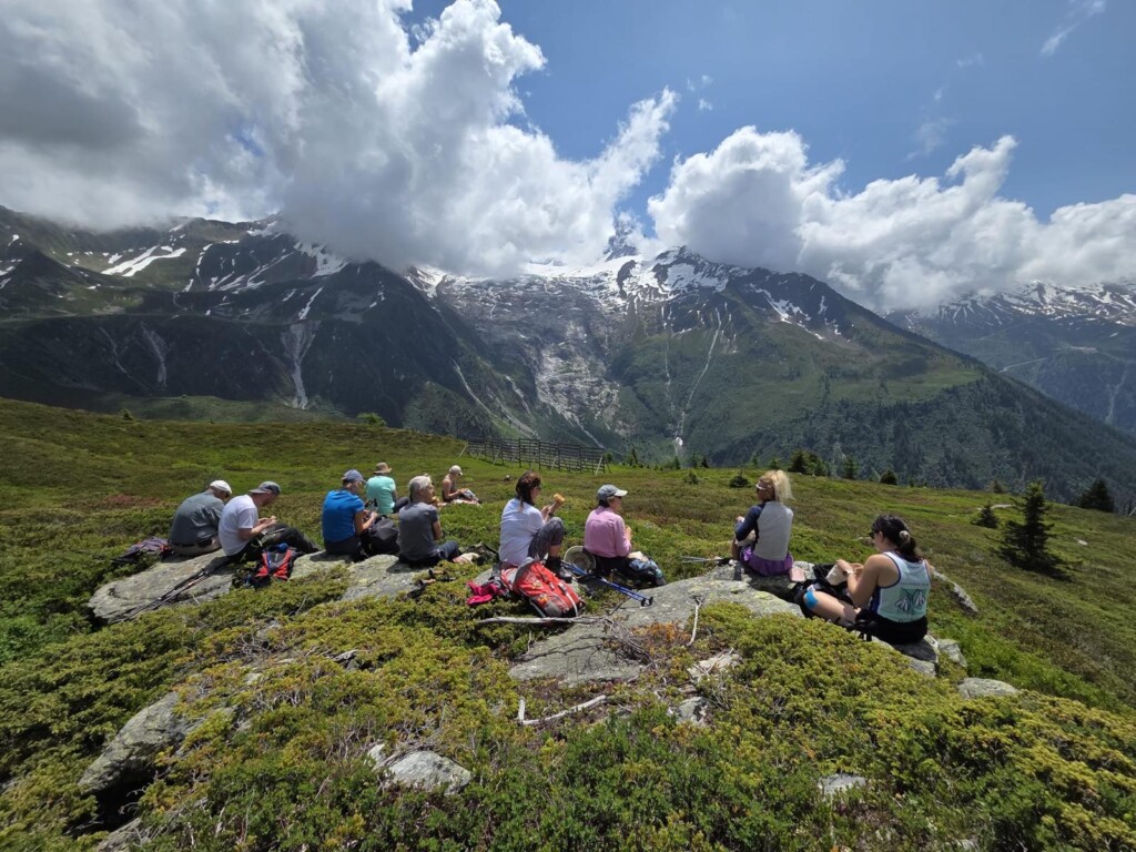 A group of walkers sit eating lunch looking out over Mont Blanc