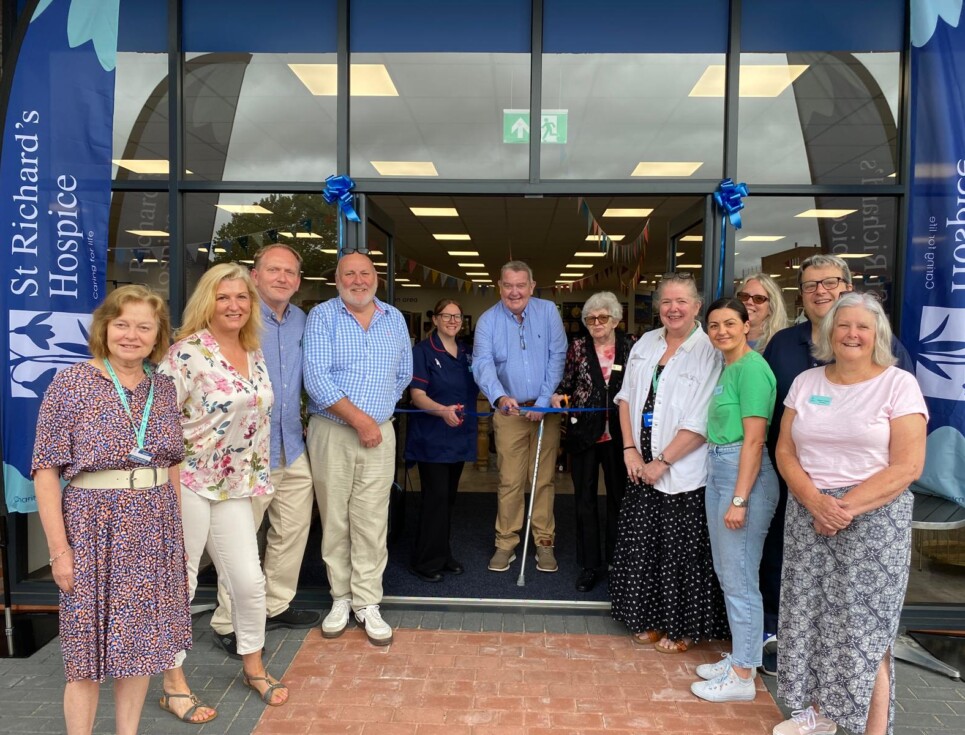 A group of people gathered for a photograph outside the hospice's superstore. Three people in the middle stand behind a ribbon, ready to cut it and officially open the store.