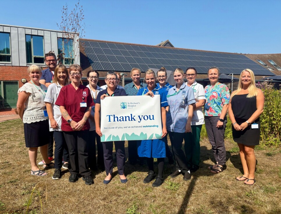 Hospice staff stand in the hospice gardens holding a banner which reads 'thank you'